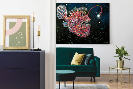 A colorful abstract painting of a bioluminescent anglerfish on a black background, displayed on a white wall in a modern living room setting above a teal velvet sofa.