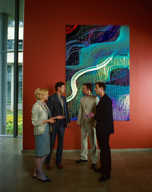 Four people standing and discussing a large abstract painting on a red wall in a gallery or museum setting. Lost Creek Feather art by Doug LaRue