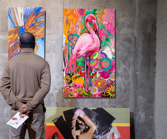 A person stands with their back to the camera, viewing a large, highly colorful abstract painting of a pink flamingo on a gallery wall. Another colorful painting is visible on the left, and a large red and black artwork is leaning on the floor in the foreground. Pink Flamingo by Doug LaRue