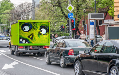 Green truck with Crazy Eyes oil painting on the cargo door in heavy traffic on a city street