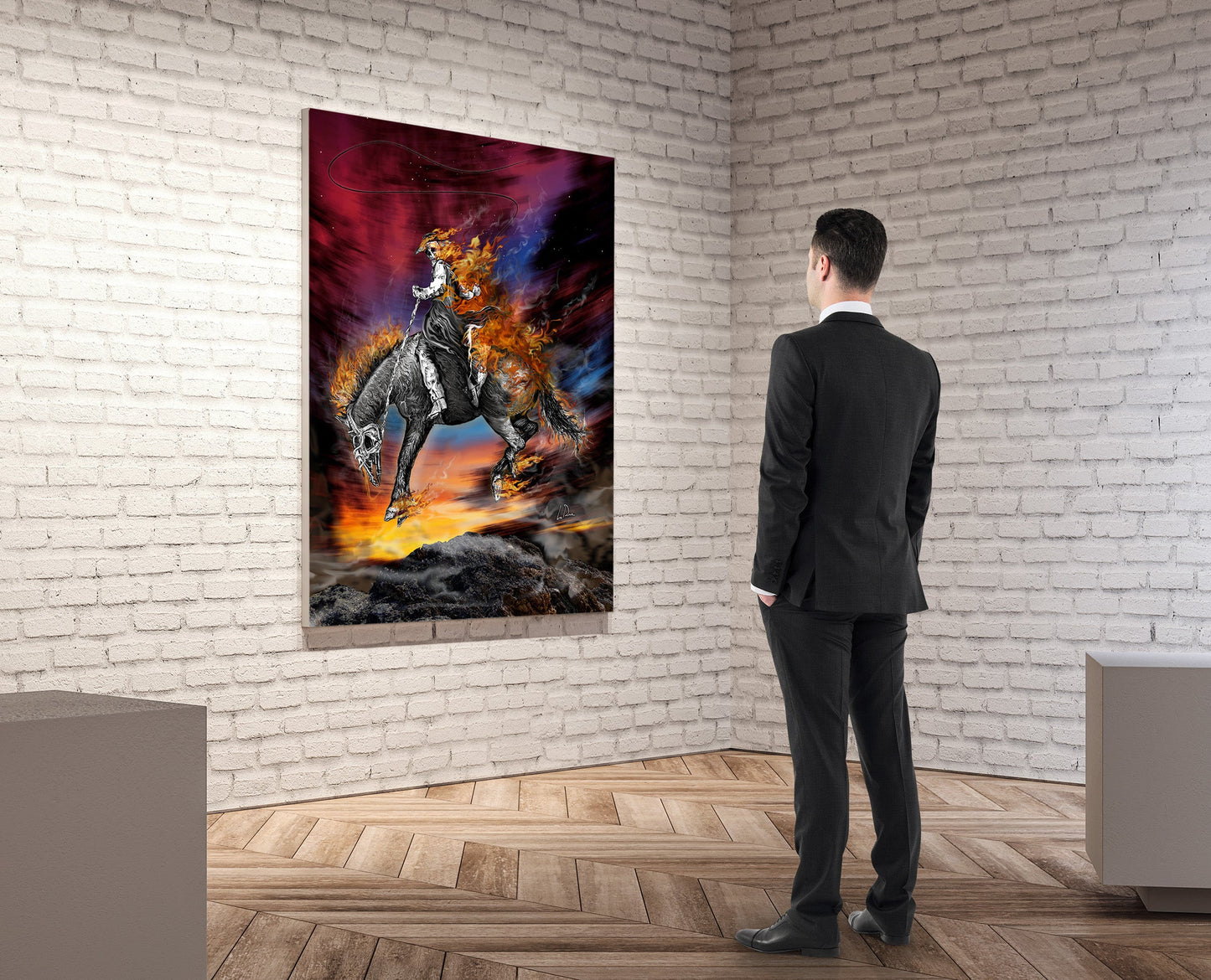A man in a dark suit stands in a gallery room with a white brick wall and wood floor, viewing a large vertical canvas print of a warrior on a horse against a fiery red, orange, and blue background.