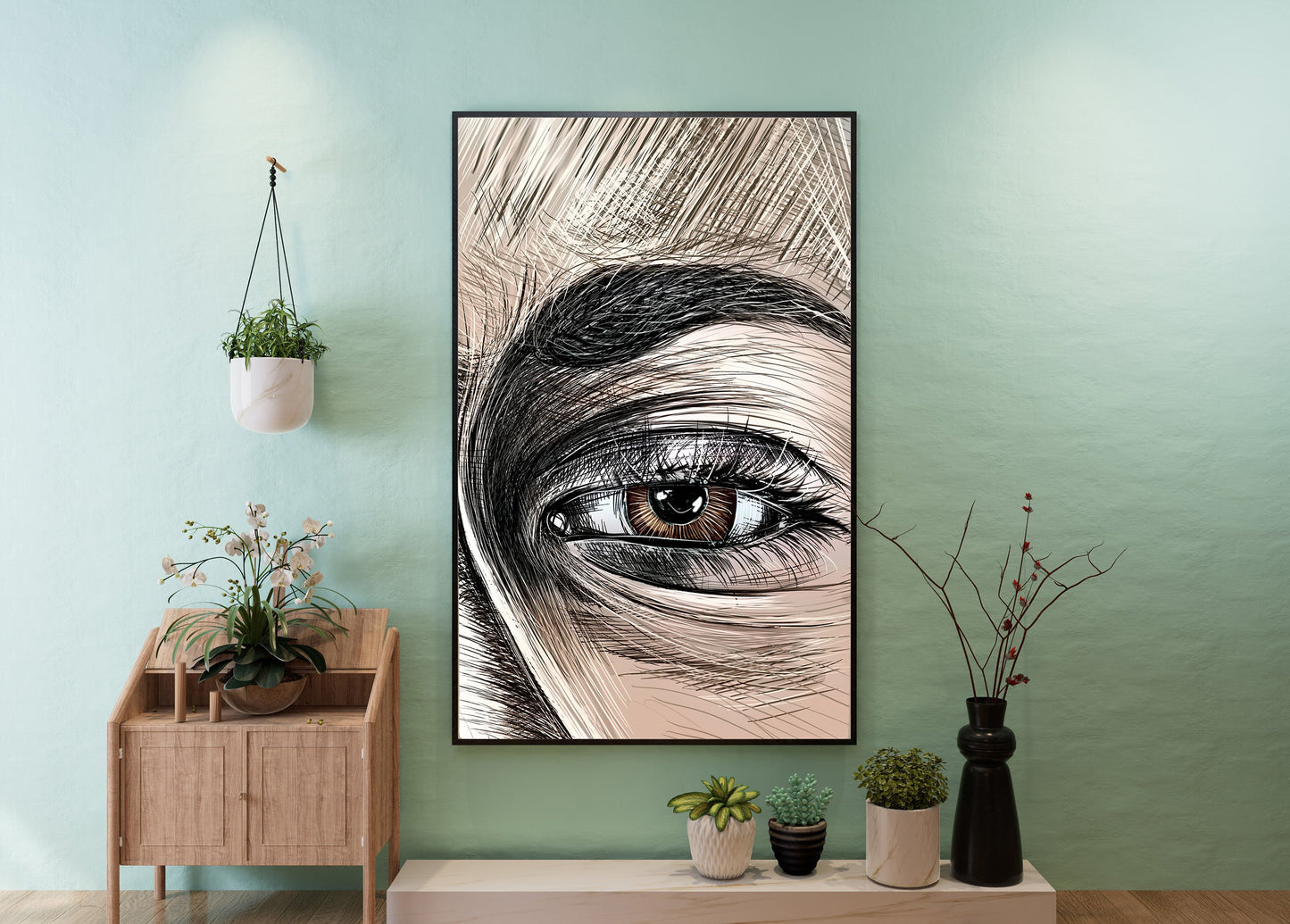 A framed vertical art print featuring a close-up pencil-style drawing of a human eye, displayed on a mint green wall above a light wood console table with small potted plants. Emma Gonzales detail by Doug LaRue