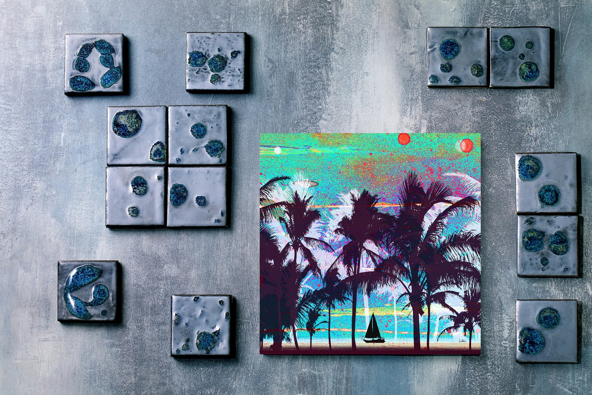 A square colorful art print depicting a tropical beach scene with palm trees, displayed on a textured gray wall alongside several matching square decorative tiles.