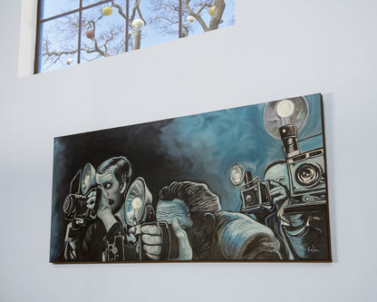 A large rectangular wall art print or painting hanging on a white wall, depicting several photographers with cameras in a dark blue and black scene. A small window is visible above the artwork. Ringside Press oil painting by Doug LaRue