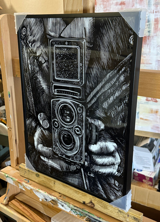 Leather Twin Lens Black and white drawing of a vintage camera held by hands, framed in black metal