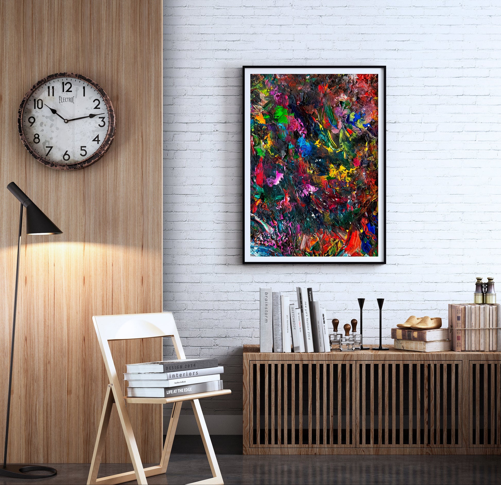 A colorful abstract canvas art print in a black frame hangs on a white brick wall in a modern, stylishly decorated room with a wooden credenza, books, a folding chair, and a wall clock. V19 Brentwood by Doug LaRue